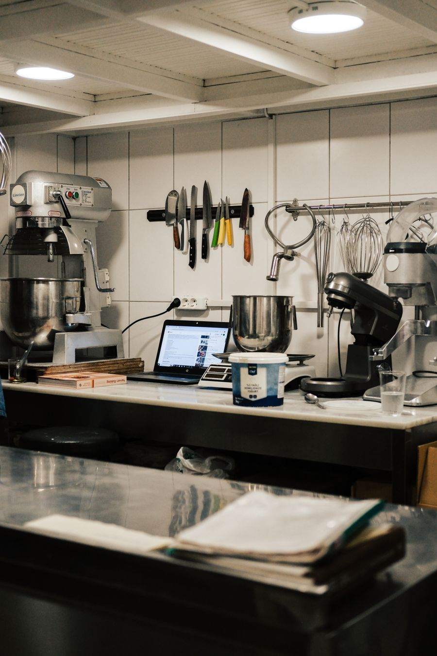 A commercial kitchen with mixers and a laptop on the counter